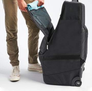 image of a person inserting a towel into the mesh zipper opening inside of the Roam Padded Roller Backpack